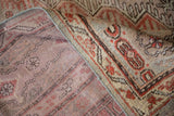 Distressed Khotan carpet with textured brick red pile folding to reveal hand-knotted foundation.