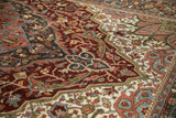 Distressed Heriz carpet showing serrated floral outlines, trefoil vines in burgundy and blue.