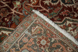 Folded vintage Heriz rug corner showcasing worn red, blue, green floral motifs and hand-knotted back.