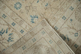 Distressed beige Sparta carpet pile with blue floral motifs and visible machine-bound edge.