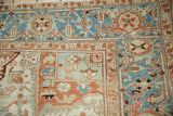 Distressed vintage Heriz carpet corner with a geometric border in terracotta and dusty blue.