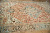 Large-scale starburst medallion on a distressed Heriz carpet in faded terracotta and dusty blue hues.