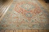 Angled view of the distressed corner of a Persian Heriz carpet in terracotta and blue.
