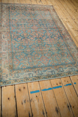 Distressed vintage Hamadan rug corner showing a weathered indigo blue border and soft fringe.
