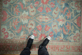 Looking down at the worn, decorative pattern of a vintage distressed Persian Malayer rug.