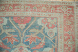 Even wear to the knot heads on a distressed Malayer rug's corner in blue and raspberry.