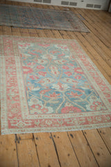 Angled view of a vintage Malayer rug's faded floral pattern and traditional border.