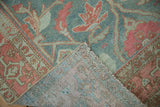 Corner of vintage Malayer rug folded to show the hand-knotted foundation and low, worn pile.