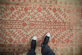Worn texture of an antique Khotan rug with coral red pomegranate fruits and long stemmed vines.
