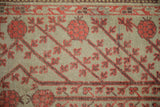 Coral red pomegranate fruits on diagonal vines across a worn, sea foam green hand-knotted field.