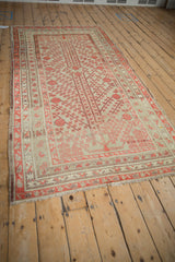 Angled view displaying the full pattern of a distressed antique Khotan rug with pomegranate motifs.