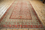 Angled perspective down the length of a distressed antique Khotan rug.
