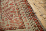 Multiple geometric floral borders in coral, plum, and saffron on a distressed antique Khotan rug.