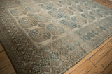 Angled view across the geometric guls and detailed main border of a distressed Ersari carpet.