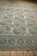 Low-angle view of a distressed vintage Ersari carpet's geometric border and worn, low-pile texture.