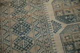 Evenly worn low pile texture of a distressed Ersari rug with indigo and copper geometric guls.