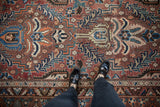 Feet on vintage Persian Baktiari carpet, displaying chestnut, sapphire blue, madder red floral motifs.