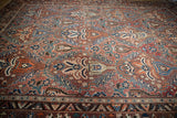 Intricate floral palmette and dragon-inspired border on vintage Baktiari carpet in chestnut, blue, and red.