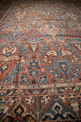 Vintage Baktiari carpet's intricate palmette design in madder root red, sky blue, and brown.