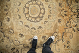 Close-up of a vintage Kars carpet's even wear and concentric medallion in beige and charcoal.