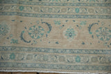 Fringe and worn beige and dusty blue border patterns of a vintage Tabriz rug.