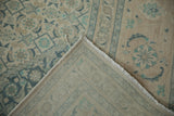 Vintage distressed Tabriz carpet corner, displaying worn ivory pile with blue motifs and tight foundation.