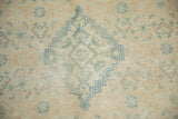 Distressed Tabriz carpet close-up: dusty teal Herati motif, ivory field, and even pile wear.