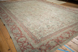Angled view of a vintage distressed carpet showing the faded red border and worn pile.
