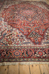 Angled view of a vintage Ahar carpet's ivory spandrel and detailed cherry red field.