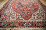 Angled view of a vintage Ahar carpet highlighting its detailed spandrels and cherry red field.