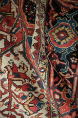 The substantial body and dense wool pile of a vintage Ahar carpet with cherry red and navy motifs.