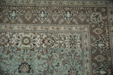 Distressed vintage Persian Qom rug corner with intricate aqua, coffee brown, and mauve floral patterns.