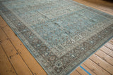 Distressed vintage Qom rug with intricate blue floral field and coffee brown border.