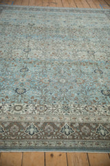 Distressed Qom carpet detail: intricate floral motifs, aquatic blue, muted brown, and subtle wear.