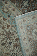 Distressed floral pile in aqua and brown, showing folded machine bound side and woven foundation.