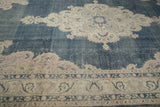 Distressed vintage Sparta carpet: dusty cobalt blue field with visible wear, ivory, pink border.
