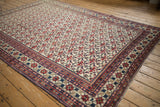 Vintage Baktiari carpet corner showing brick red floral field and pomegranate border.