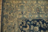 Worn pile texture on the sand and blue floral palmette border of a vintage Lilihan carpet.