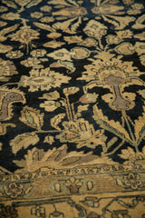Evenly worn pile of a vintage Lilihan rug, showing beige floral designs and vinery on a dark navy background.