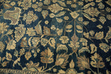 Close-up on the distressed pile, showing sand-colored floral vinery on an abrashed navy blue field.