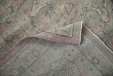Distressed Sparta carpet's folded edge, revealing faded pink floral patterns, worn pile, and foundation.