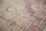 Vintage Oushak rug showing textured ivory field, faded raspberry arabesques, and muted border.