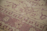Detail of vintage distressed Oushak rug showing low pile, faded ivory and dusty raspberry vinery.