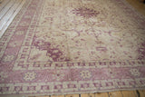 Distressed Oushak rug with ivory, dusty raspberry border showing delicate floral motifs.