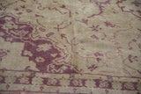 Close-up of distressed vintage Oushak rug with low pile, ivory and dusty raspberry vinery.