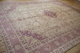 Distressed vintage Oushak rug's worn ivory pile showing faded dusty raspberry patterns.