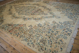 Dense clusters of blossoms on vintage Kerman carpet in sky blue, apricot, and cream.