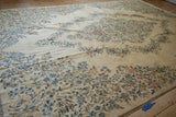Dense clusters of sky blue, apricot, and cream floral motifs on a vintage Kerman rug.
