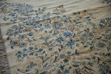 Dense blue floral blossoms and ivory fringe on a vintage Kerman rug corner.