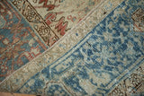 Folded vintage Mehrivan carpet showing distressed pale blue, terracotta patterns and machine-bound edge.